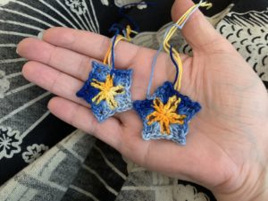 a pair of blue crochet flowers with yellow centres